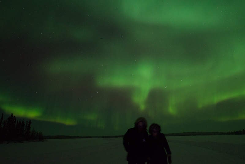 The two owners of AT Frosted Lens under the northern lights in Yellowknife, NWT, Canada