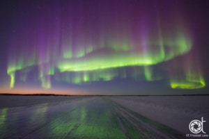 Northern lights over frozen lake and reflecting on ice road in Yellowknife, Canada